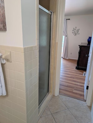 Une salle de bain avec une douche, des murs carrelés et un plancher en bois.