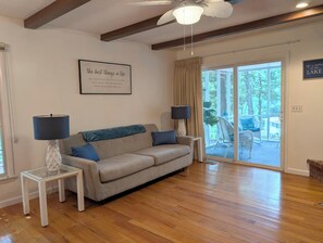 A living room with a sofa, two side tables with lamps, a ceiling fan, and a large window with curtains. - Beautiful & Spacious 3 bedroom/3 bath home with stunning views of Norfolk Lake (mountain home)
