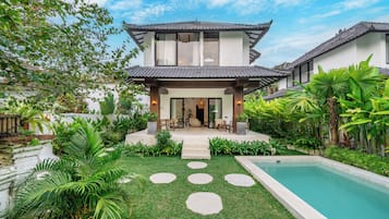 Una casa moderna con piscina, rodeada de exuberante vegetación y un jardín cuidado.