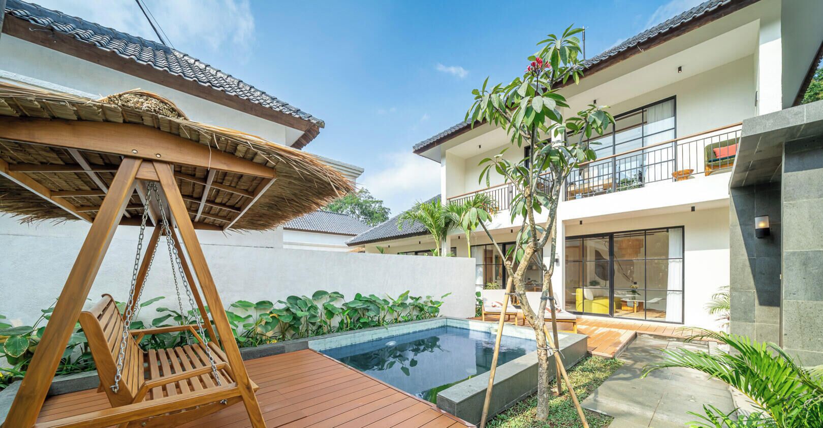 Een modern huis met een zwembad, een houten schommel en een balkon.