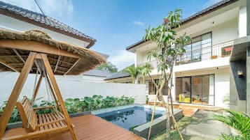 A modern house with a swimming pool, a wooden swing, and a balcony.