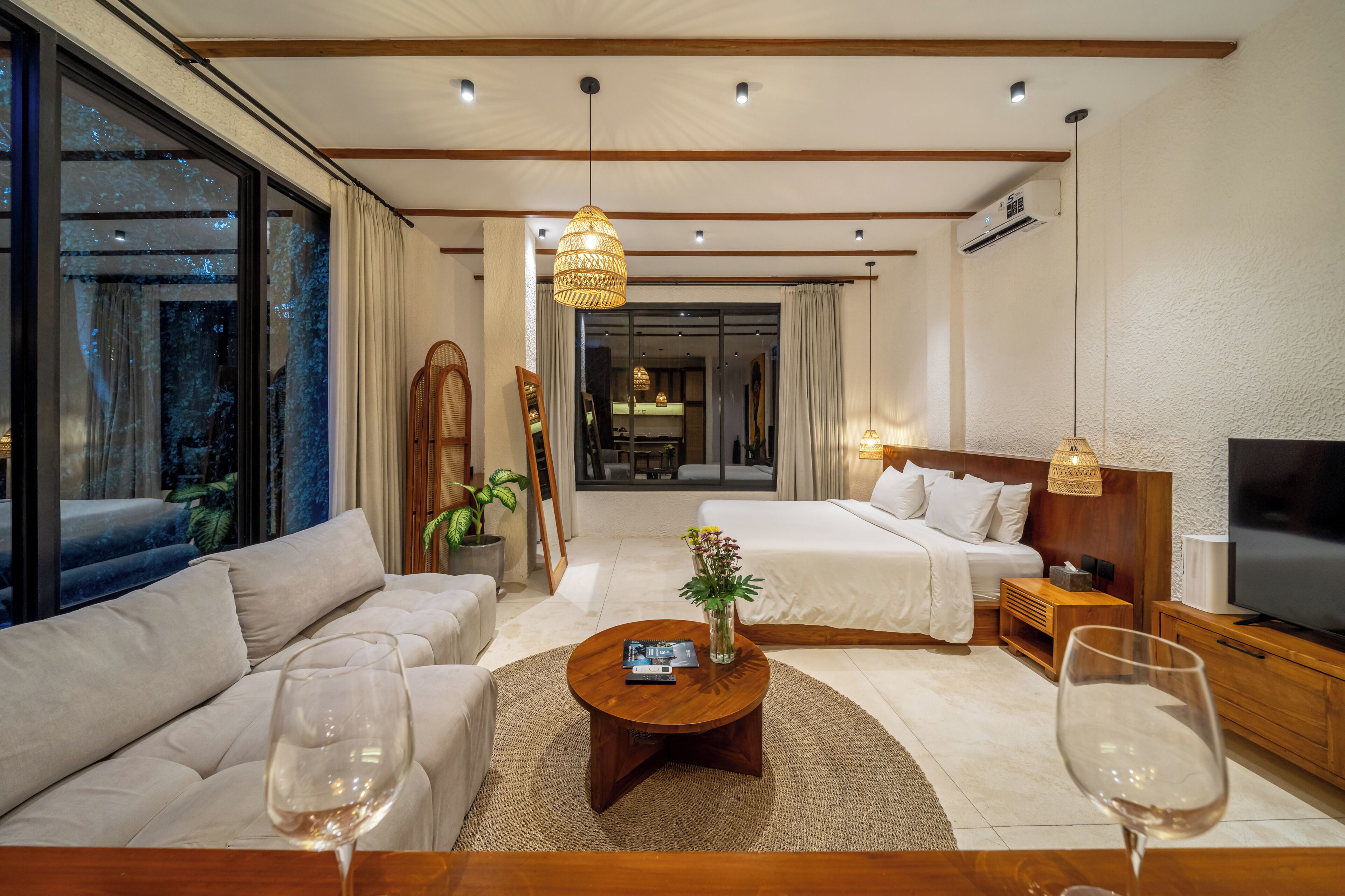 A hotel room with a sofa, a bed, a TV, and a coffee table.