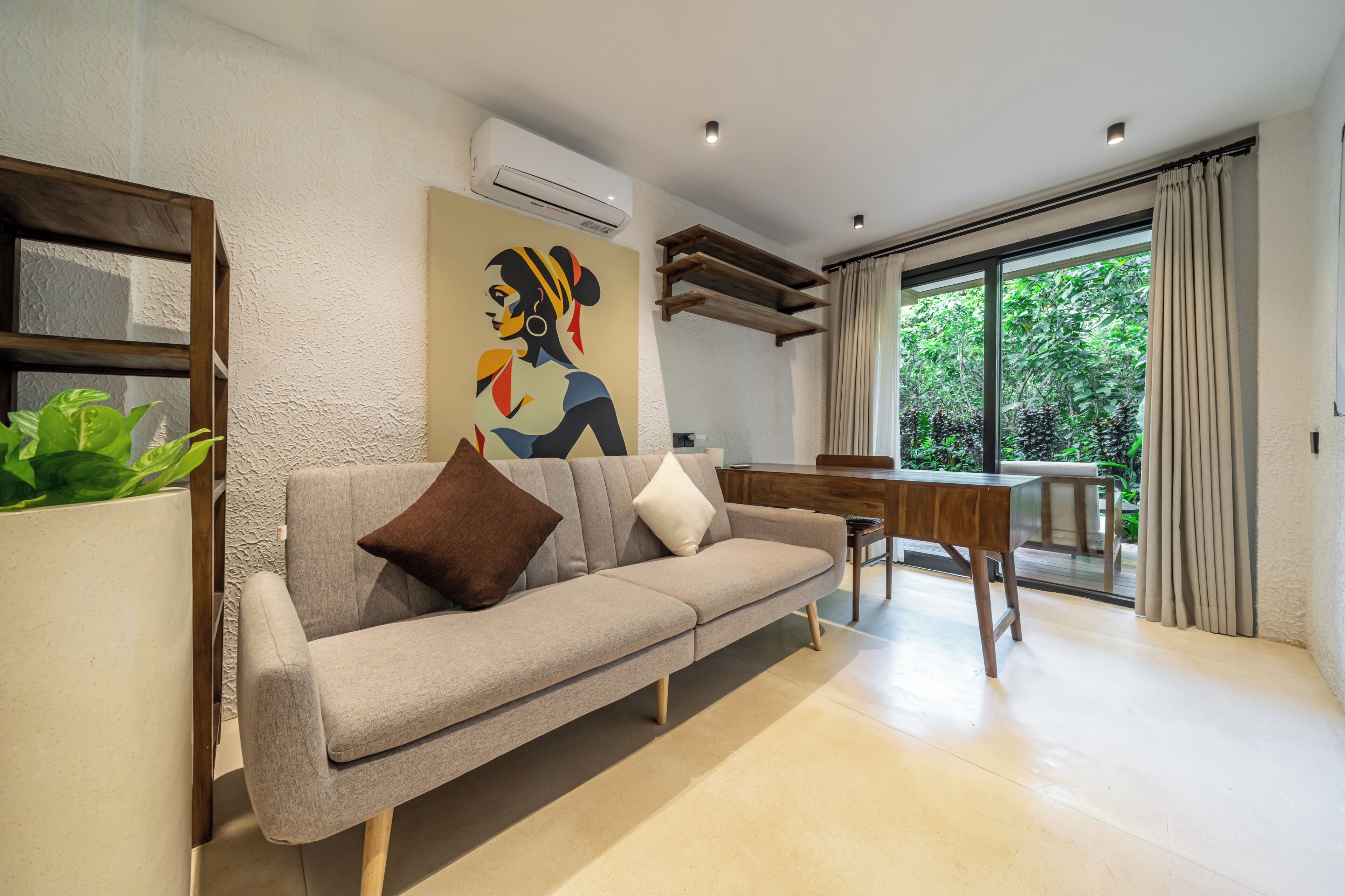 Un salón moderno con un sofá gris, una mesa de centro de madera y un ventanal con cortinas.