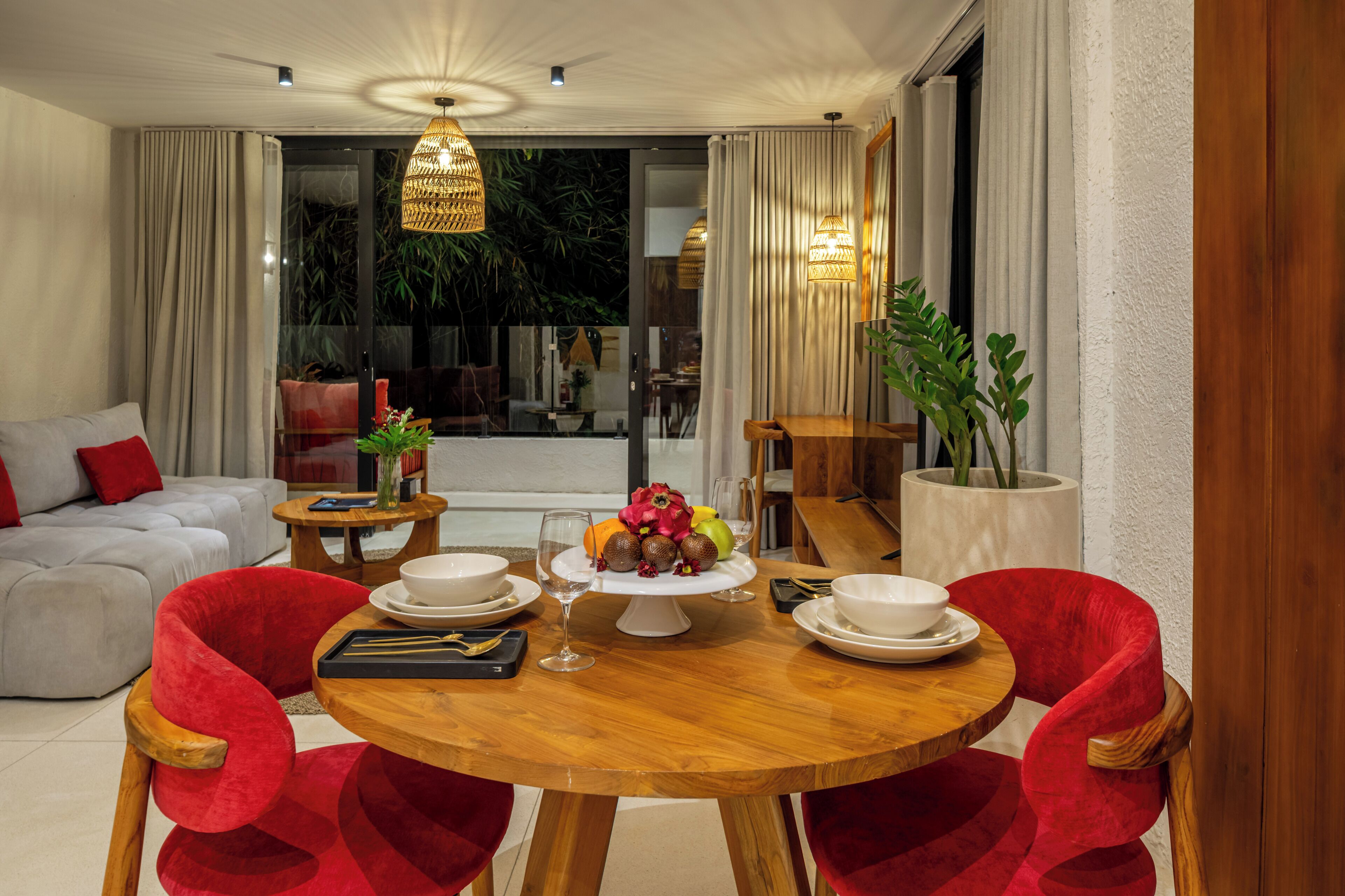 A dining area with a wooden table, red chairs, and a glass-top table with a centerpiece.