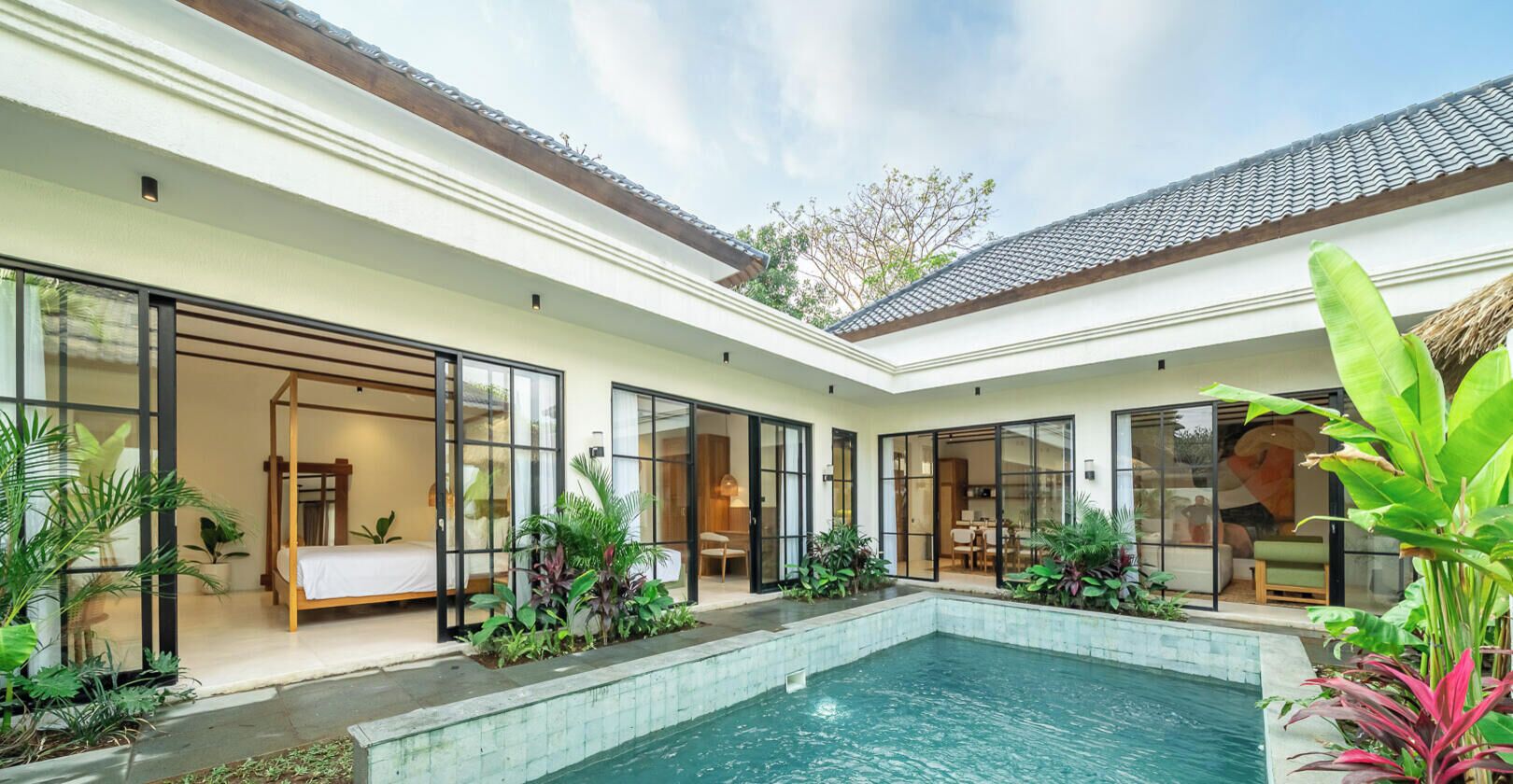Una casa moderna con piscina, puertas de vidrio amplias y plantas de interior.