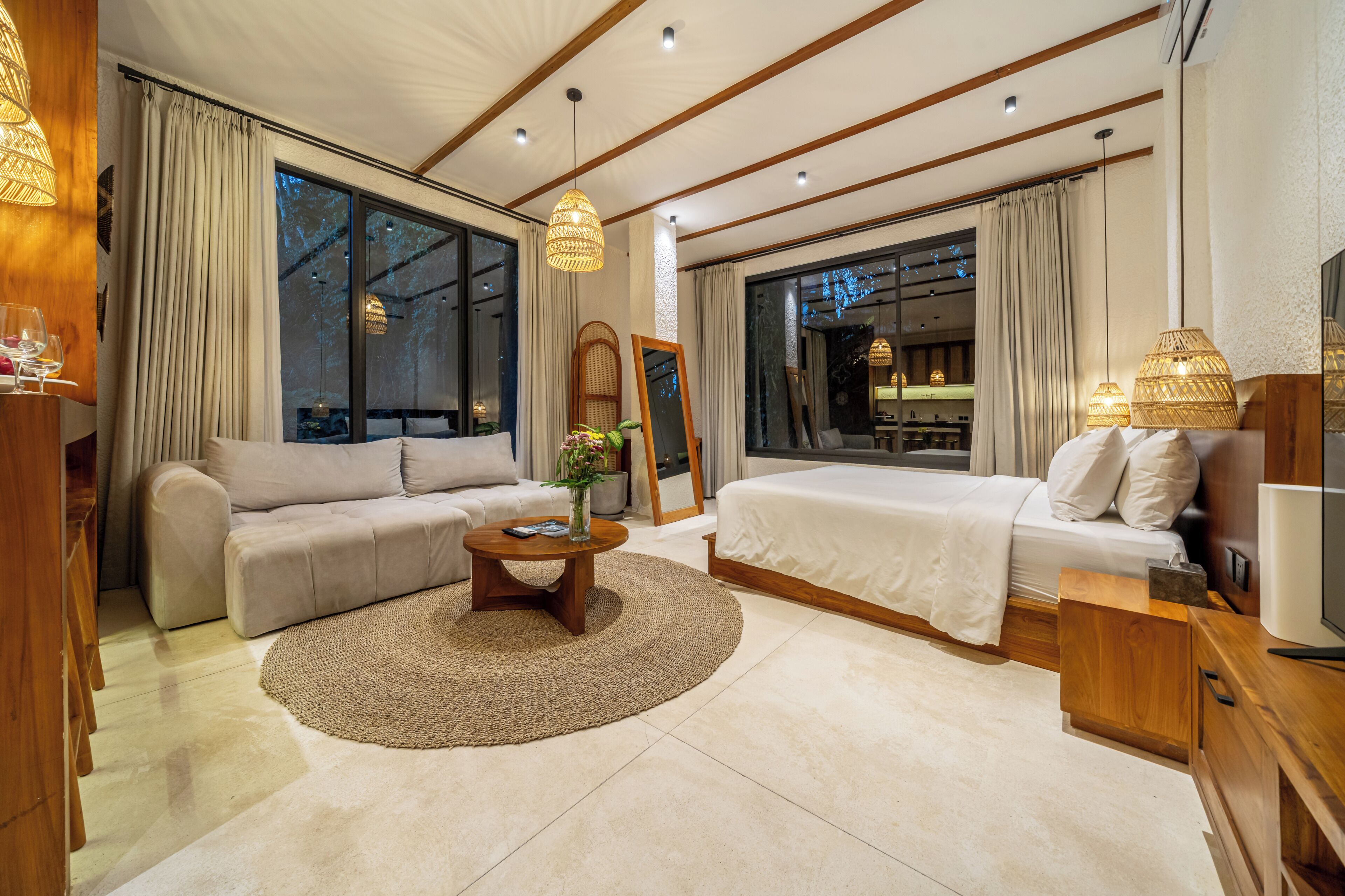 Una habitación de hotel moderna con un sofá, una cama, una mesa de centro y un televisor.