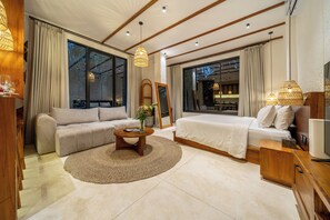 Una habitación de hotel moderna con un sofá, una cama, una mesa de centro y un televisor.