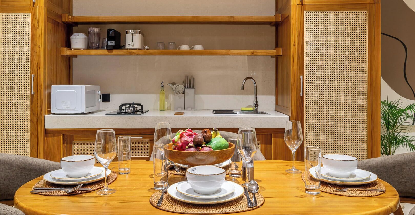 Een compacte keuken met een eethoek, voorzien van een magnetron, broodrooster en diverse keukengerei.