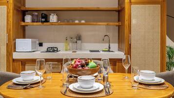 A compact kitchen with a dining area, equipped with a microwave, toaster, and various kitchen utensils.