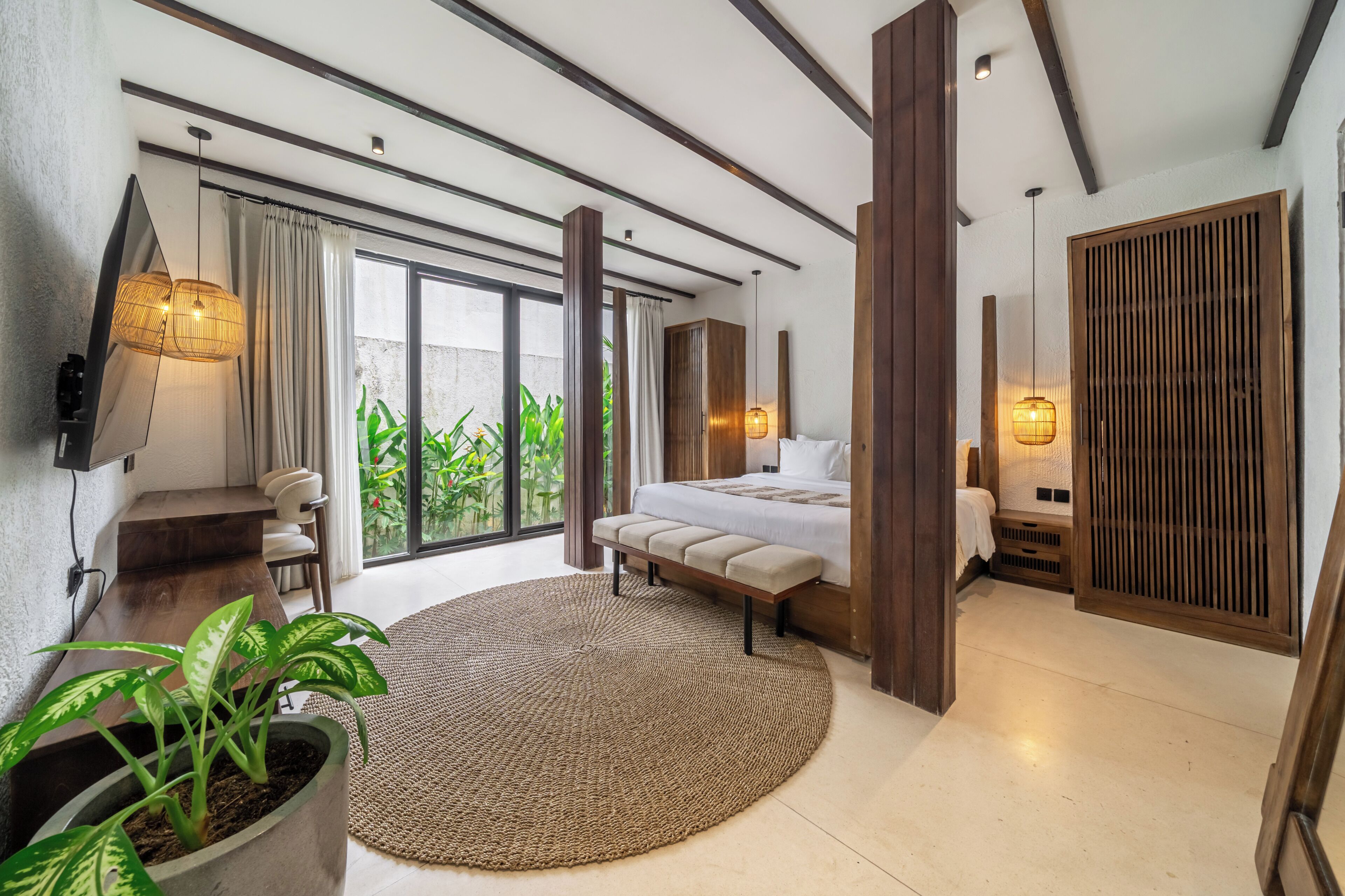 A modern bedroom with a bed, seating area, and a large window.