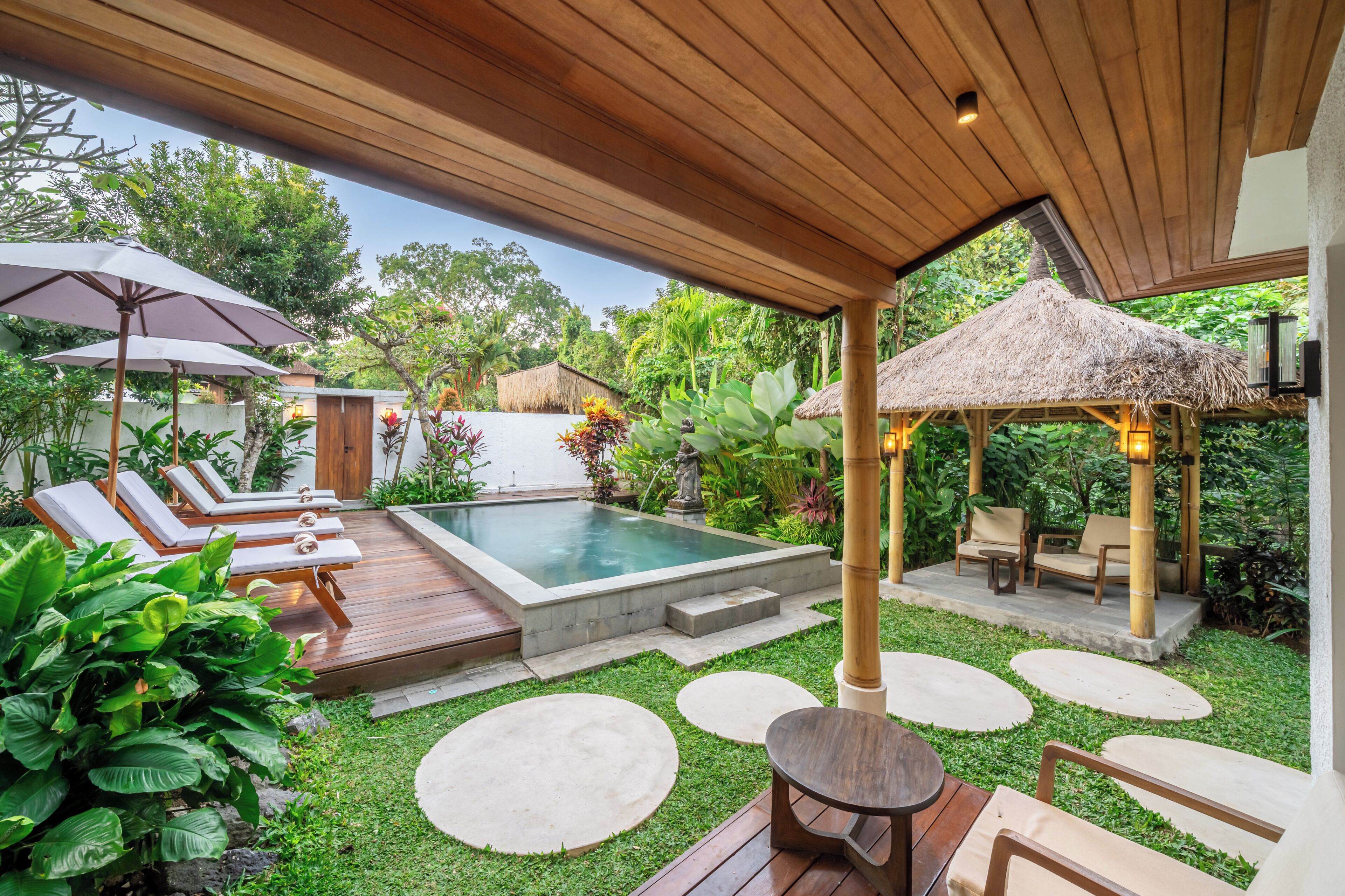 A pool area with lounge chairs, a hot tub, and a gazebo.