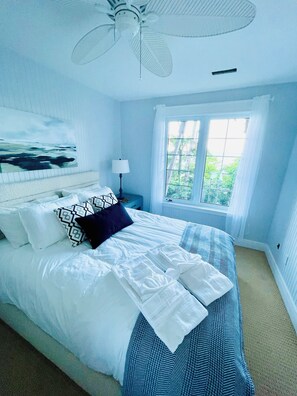 A bedroom with a bed, a nightstand, a lamp, a ceiling fan, and a window with curtains. - Waterfront Cottage - Bayfield, Lake Huron (Bluewater)