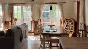 A spacious living area with a dining table, wooden chairs, and a ceiling fan.
