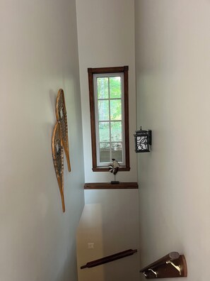 A room with a window, a wall-mounted light fixture, and a wooden object on the wall. - Cozy Chalet with private SPA in the Laurentians (Sainte-Agathe-des-Monts)