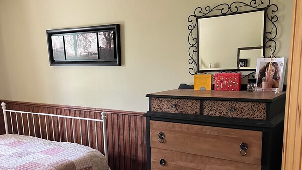 A bedroom with a bed, dresser, mirror, and a framed picture on the wall.