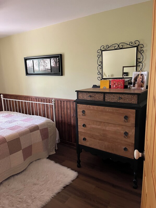 A bedroom with a bed, dresser, mirror, and a framed picture on the wall.