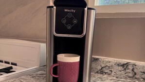 En kaffemaskine med en kop på en køkkenbordplade.