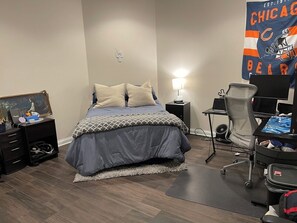A bedroom with a bed, bedside tables, a desk, and a chair.