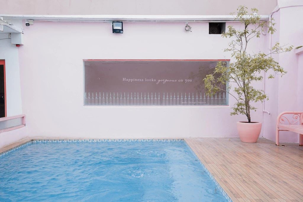 Una piscina con una pared rosa y un banco.