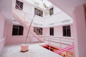 A multi-level interior with a central staircase, a potted plant, and a red carpeted area.