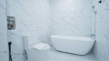 Un baño moderno con una bañera independiente, un inodoro y una zona de ducha.