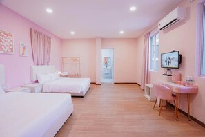 A hotel room with two beds, a desk with a chair, a television, and an air conditioning unit. - The Pink Boutique (George Town)