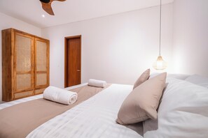 Ein Schlafzimmer mit einem Bett, einem Holzschrank, einer Tür und einer Pendelleuchte.