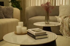 A living room with a round coffee table, a sofa, and a vase with flowers.