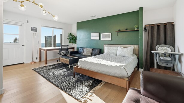 Een slaapkamer met een bed, een bureau, een stoel, een bank, een raam en een groene wand.