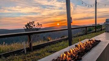 A fire feature with a sunset view, outdoor seating, and a railing.