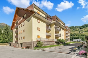 A multi-story hotel with balconies and a parking area.
