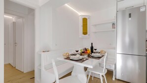 Una cocina moderna con armarios blancos, un refrigerador empotrado y una mesa de comedor para cuatro.