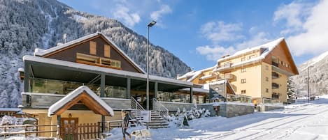Un bâtiment moderne abritant une station de ski, doté d’une entrée couverte, d’une structure en bois et offrant une vue sur les montagnes.