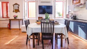 A dining area with a table, chairs, a television, and a kitchen area with cabinets and appliances. - Nobile Studio in the Historic Town, Koper, Slovenia (Koper)