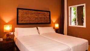 Hotellihuone, jossa on suuri sänky, kaksi yöpöytävalaisinta, ikkuna verhoilla ja seinään kiinnitetty valaisin.