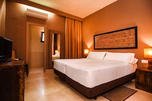 Una habitación de hotel con una cama grande, televisión, escritorio y espejo.