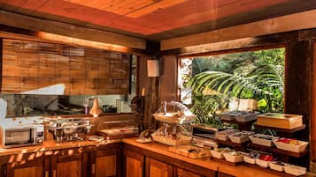 A wooden kitchen with a large window, a microwave, a toaster, and various food containers.