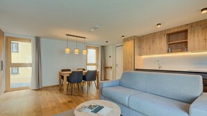 A modern living room with a sofa, a round coffee table, and a dining area with chairs and a table.