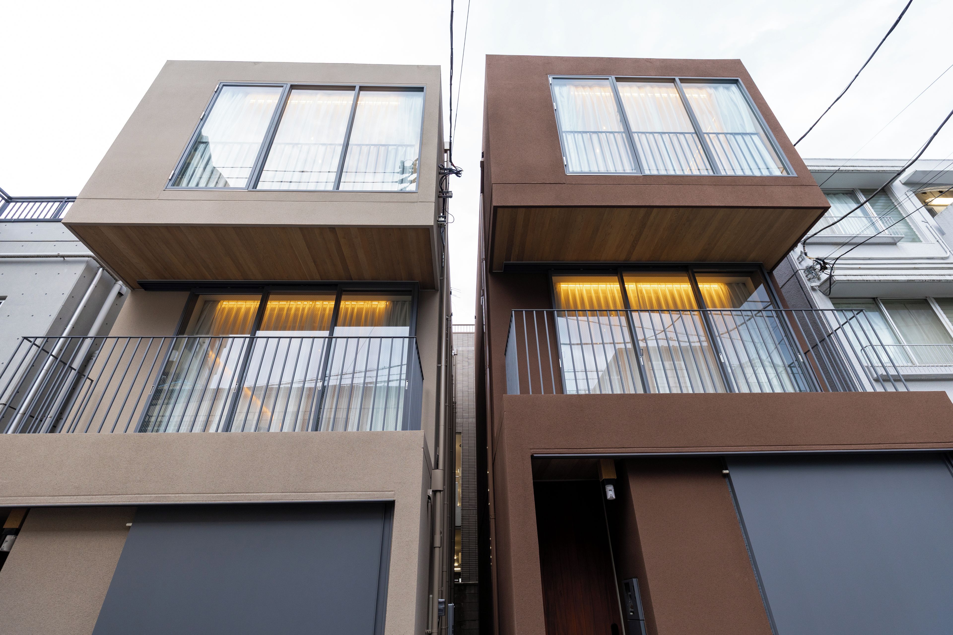 A modern two-story building with a flat roof, large windows, and a balcony.
