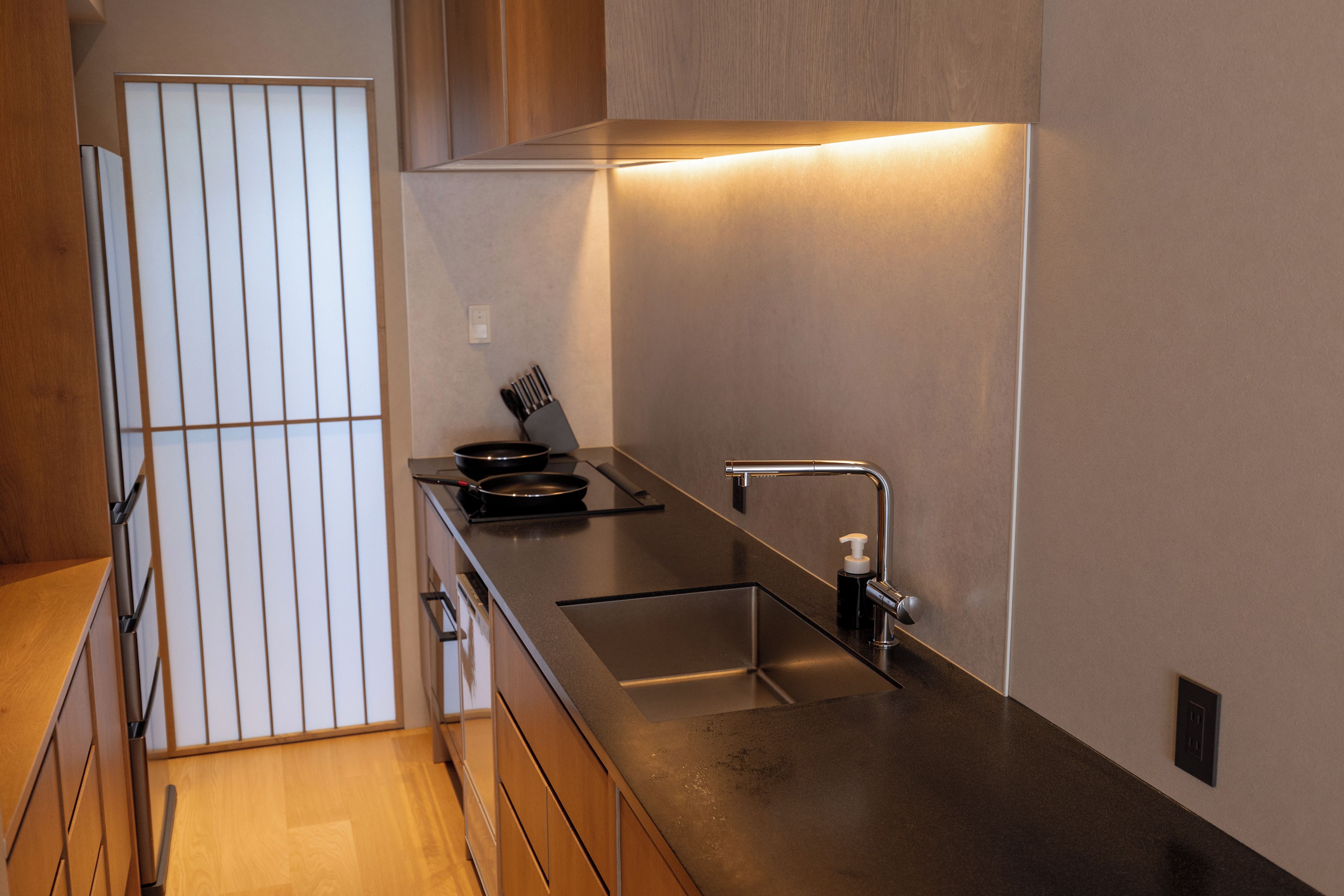 Una cocina moderna con encimera de acero inoxidable, estufa integrada y un lavamanos.