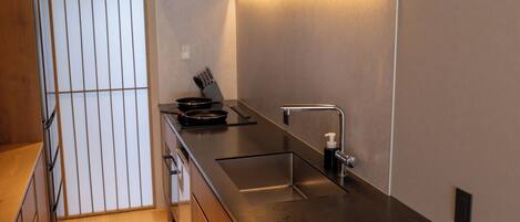 Una cocina moderna con encimera de acero inoxidable, estufa integrada y un lavamanos.