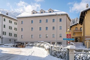 A multi-story building with a snow-covered roof and a sign indicating a nearby street.