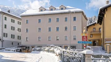 Ein mehrstöckiges Gebäude mit schneebedecktem Dach und einem Schild, das auf eine nahegelegene Straße hinweist.