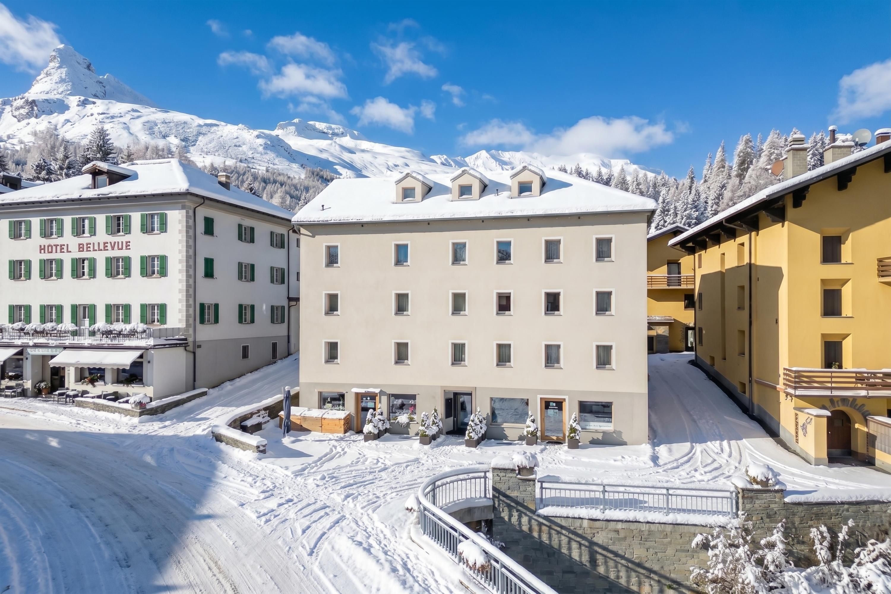 A hotel with multiple floors, a snow-covered landscape, and a mountain in the background.