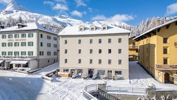 A hotel with multiple floors, a snow-covered landscape, and a mountain in the background.