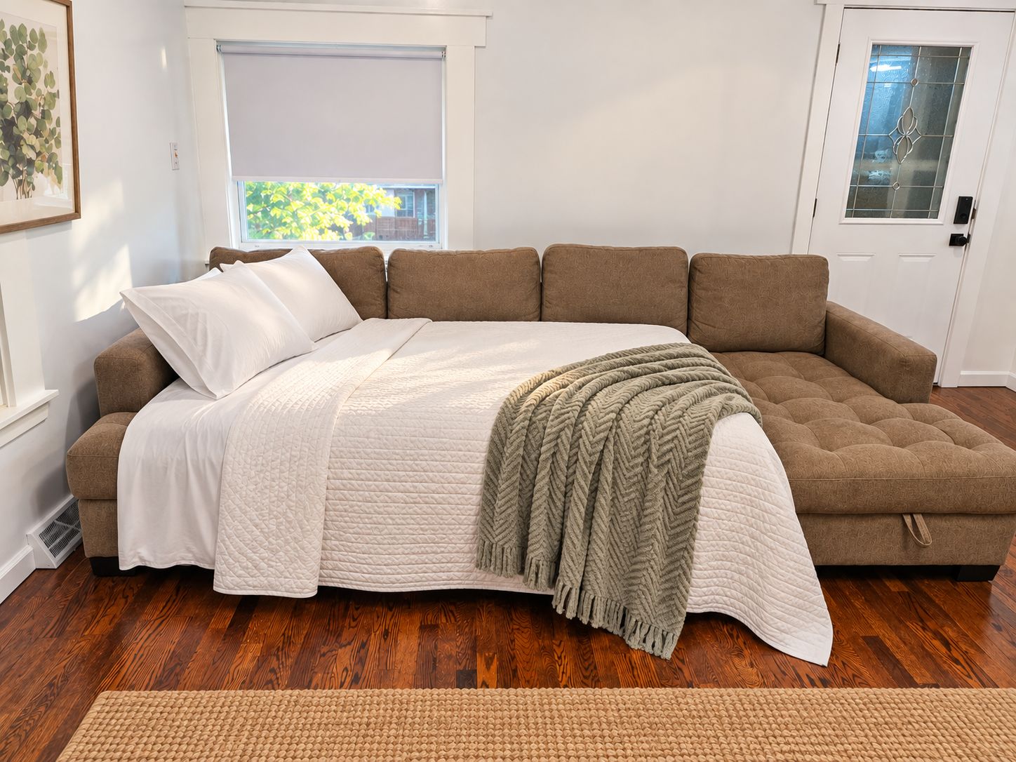 A large, L-shaped sectional sofa with a quilted white cover and a green throw blanket.