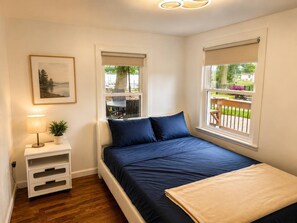 Une chambre à coucher avec un lit, des tables de chevet, une fenêtre et une vue sur l’extérieur.