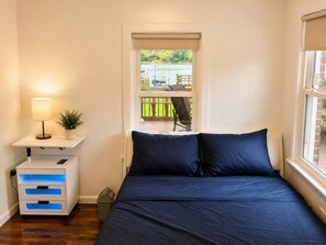Een slaapkamer met een bed, nachtkastjes, een lamp en uitzicht op een terras.