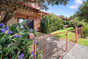 En bostadsfastighet med en inhägnad trädgård, en pergola av trä och ett stort utbud av växter.