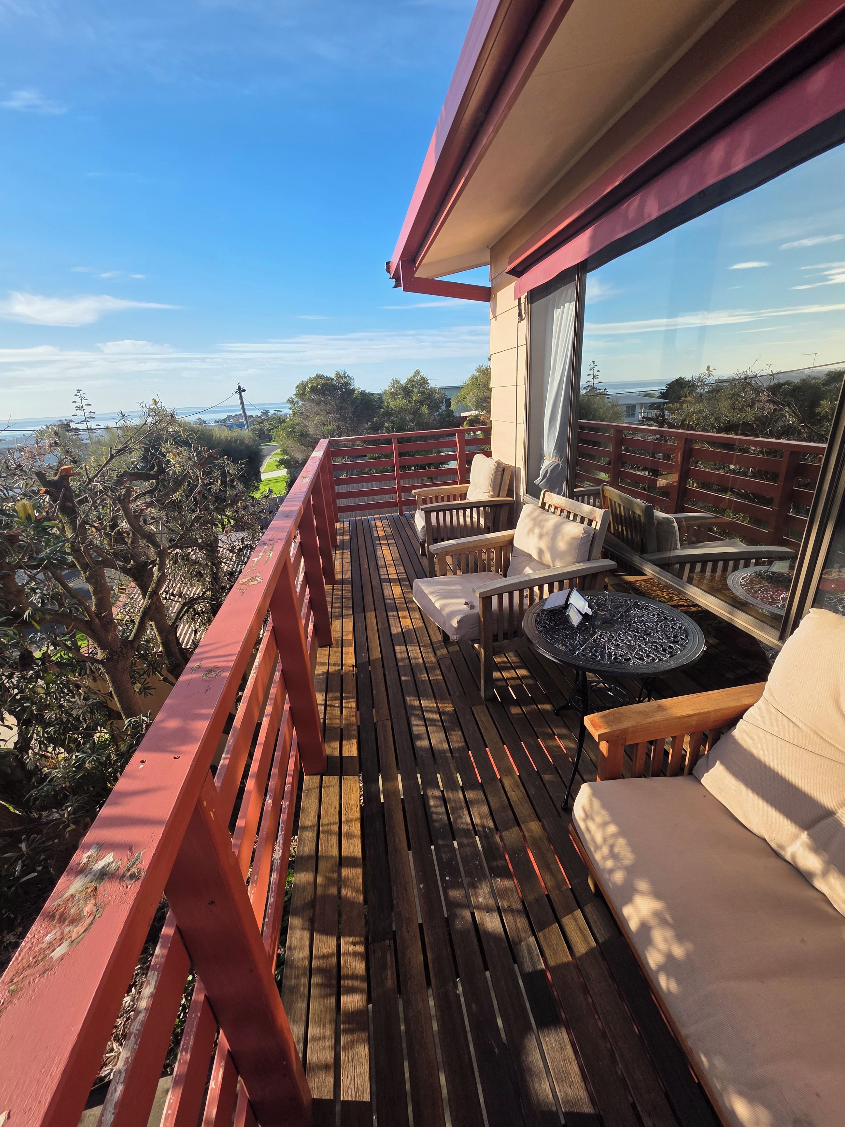 A wooden deck with outdoor seating, a fire pit, and a view of the ocean.